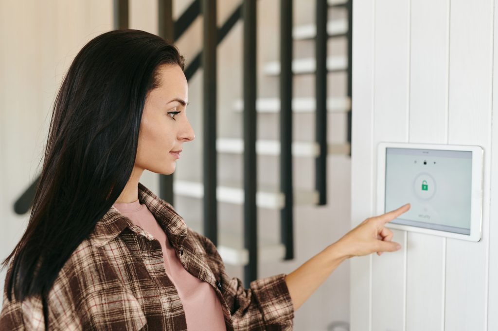 Young housewife pointing at tablet with security system